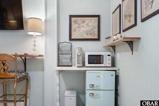 interior details with white microwave and freestanding refrigerator