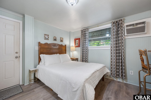 bedroom with an AC wall unit and wood finished floors