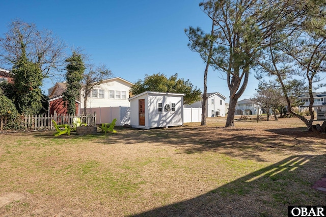 view of yard featuring a storage shed, a residential view, fence, and an outbuilding