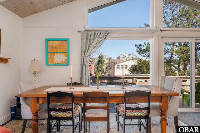 dining room with a healthy amount of sunlight, baseboards, and lofted ceiling