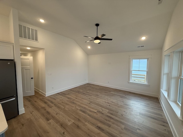 unfurnished room featuring visible vents, vaulted ceiling, and wood finished floors