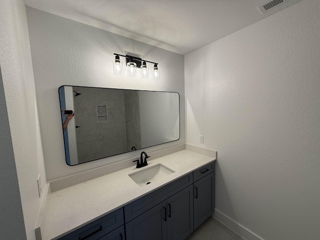 bathroom featuring a textured wall, baseboards, visible vents, and vanity