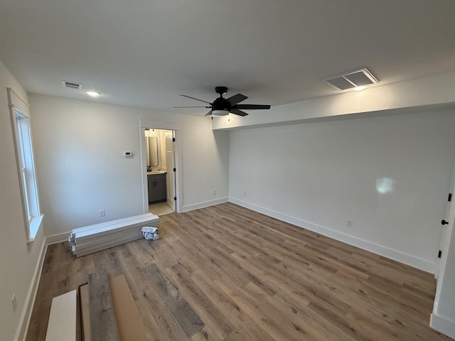 unfurnished room featuring a ceiling fan, baseboards, visible vents, and wood finished floors