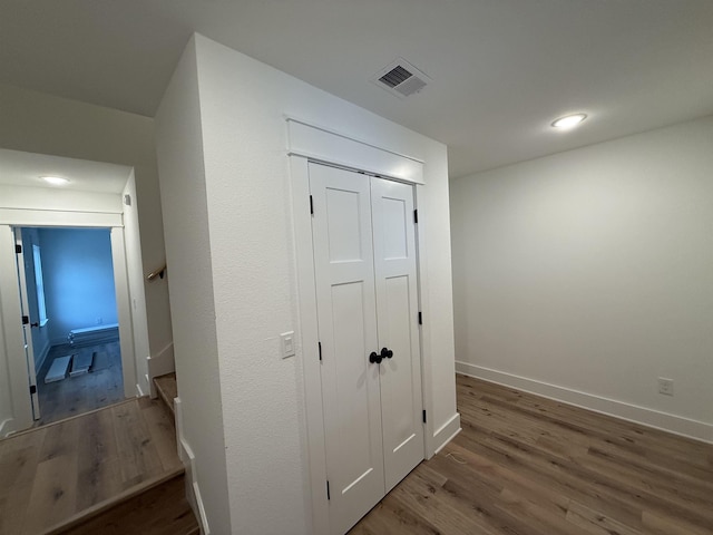 corridor featuring dark wood-type flooring, recessed lighting, visible vents, and baseboards