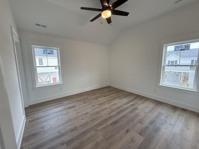 unfurnished room featuring light wood-type flooring, baseboards, visible vents, and lofted ceiling