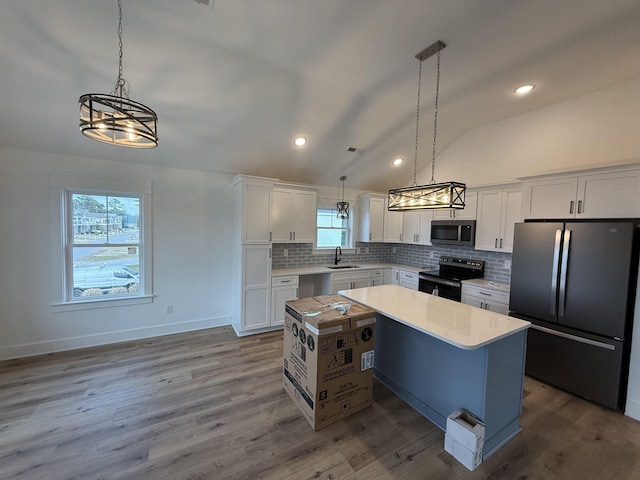 kitchen with a center island, light countertops, appliances with stainless steel finishes, white cabinetry, and a sink