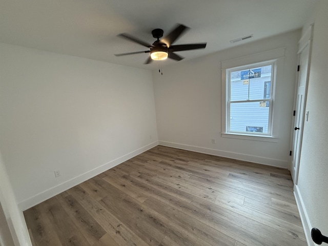 spare room with a ceiling fan, light wood-style flooring, and baseboards