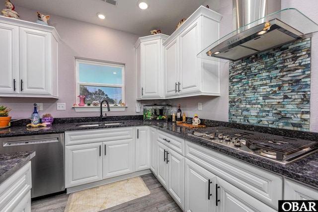 kitchen featuring white cabinets, stainless steel appliances, wall chimney exhaust hood, and a sink