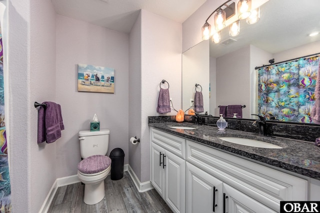 bathroom featuring toilet, wood finished floors, baseboards, and a sink