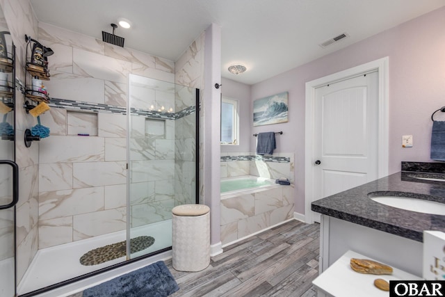 full bath with visible vents, a garden tub, wood finished floors, a marble finish shower, and vanity