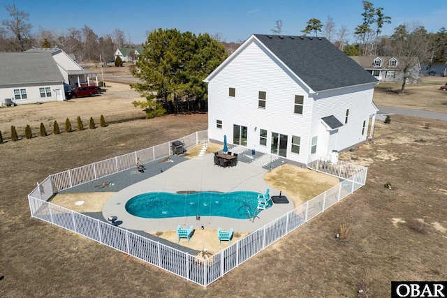 rear view of property with a patio, a fenced backyard, a fenced in pool, and roof with shingles