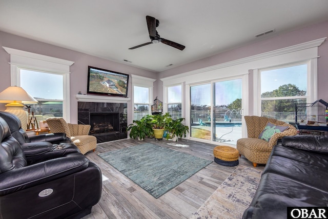 living room with visible vents, a ceiling fan, wood finished floors, and a fireplace