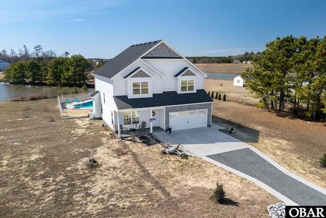 traditional home featuring concrete driveway, a porch, a garage, and roof with shingles