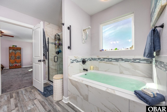 full bathroom with a shower stall, a bath, wood finished floors, and baseboards