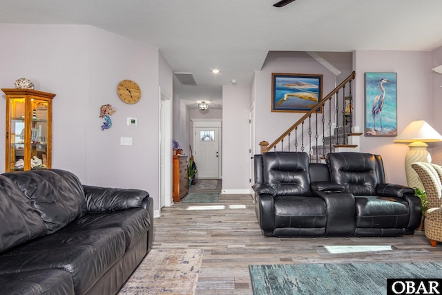 living room with visible vents, stairs, baseboards, and wood finished floors