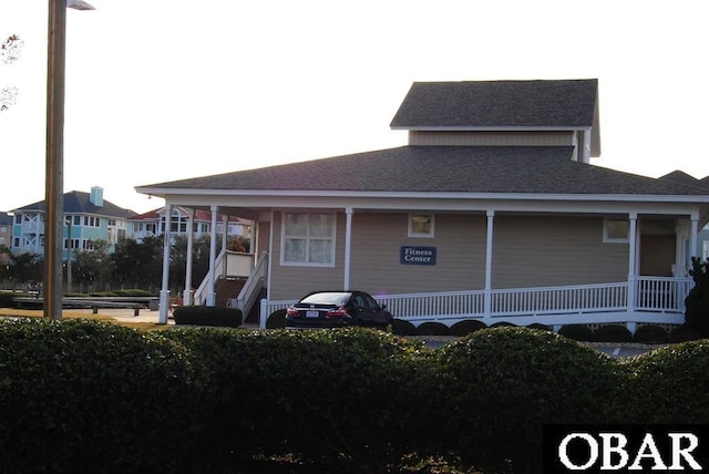 rear view of house with a porch and roof with shingles