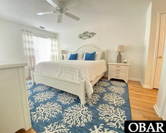 bedroom with baseboards, light wood-style flooring, visible vents, and a ceiling fan