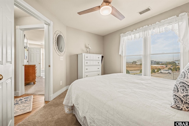 bedroom featuring a ceiling fan, light wood-type flooring, visible vents, and baseboards