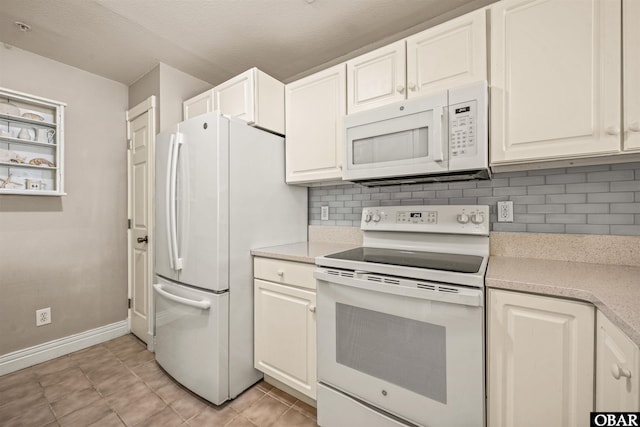 kitchen featuring white appliances, light countertops, and white cabinets