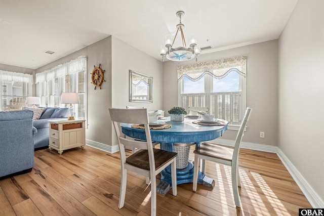 dining room featuring light wood-style floors, visible vents, baseboards, and an inviting chandelier