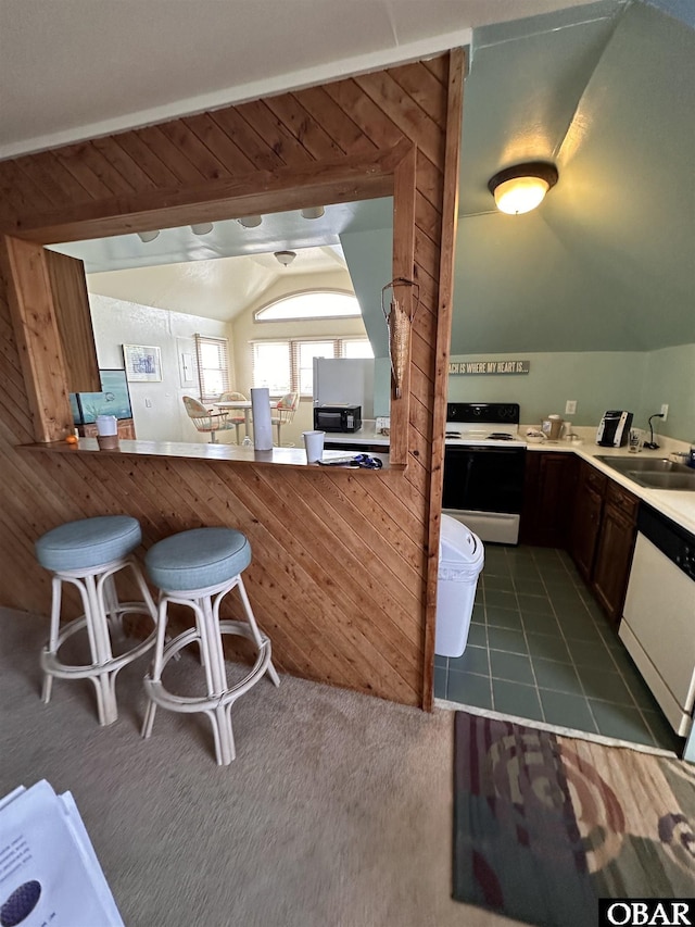 180 Irvin Garrish Hwy Unit 602, Ocracoke, NC 27960 - kitchen with white appliances, a sink, lofted ceiling, a breakfast bar area, and dark carpet