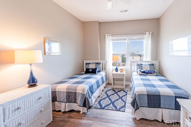 bedroom featuring a ceiling fan, visible vents, and wood finished floors