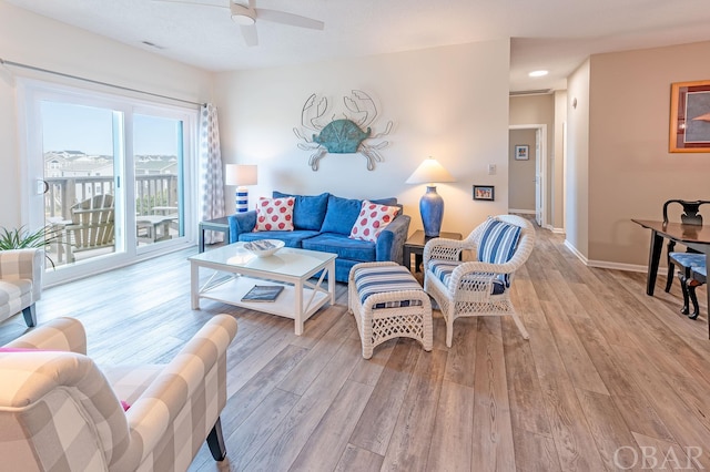 living area with visible vents, ceiling fan, light wood-style flooring, and baseboards