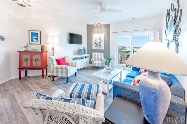 living room featuring a ceiling fan, light wood-style flooring, and baseboards