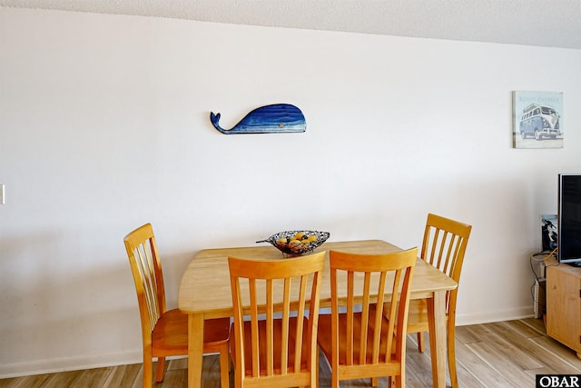 dining space with baseboards and light wood-style flooring