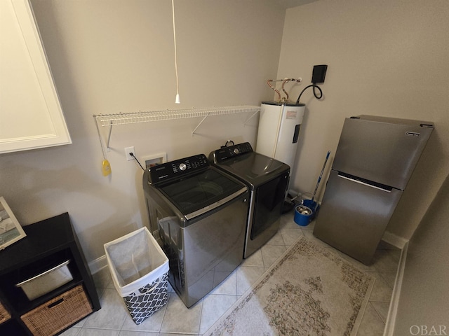 washroom with washing machine and dryer, water heater, cabinet space, and light tile patterned flooring