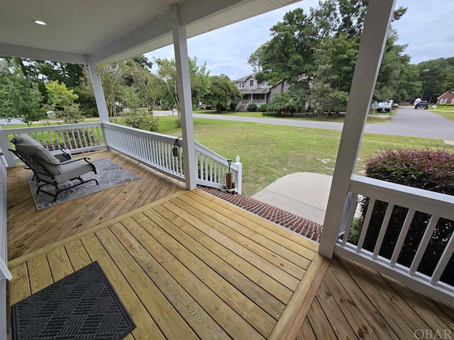 wooden deck featuring covered porch and a yard