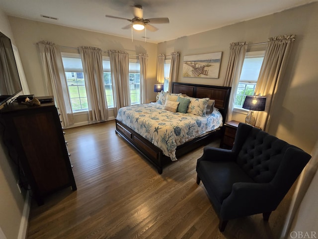 bedroom featuring ceiling fan, multiple windows, visible vents, and wood finished floors