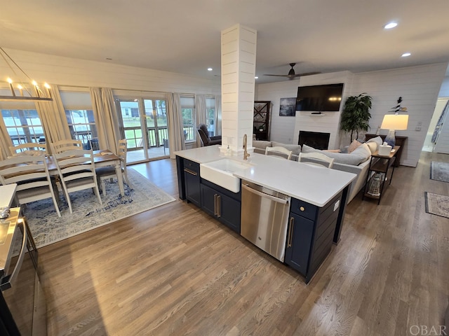 kitchen with a fireplace, a sink, open floor plan, light countertops, and dishwasher