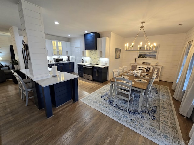 dining room with a notable chandelier, decorative columns, wood finished floors, and recessed lighting