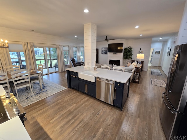 kitchen featuring dark wood-style floors, stainless steel appliances, light countertops, open floor plan, and a sink