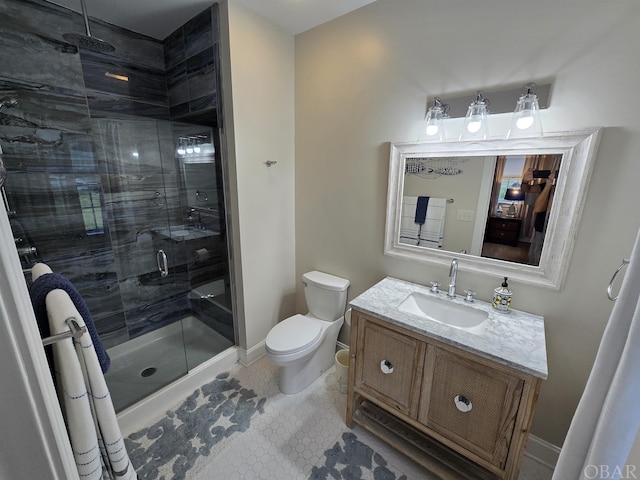 bathroom featuring toilet, a stall shower, baseboards, and vanity