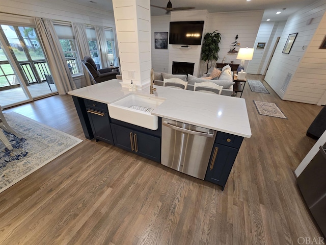 kitchen with open floor plan, light countertops, stainless steel dishwasher, and a large fireplace