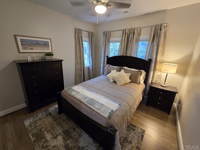 bedroom with ceiling fan, dark wood-style flooring, visible vents, and baseboards