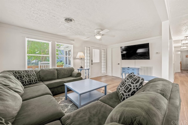 living room featuring light wood-type flooring, visible vents, and a textured ceiling