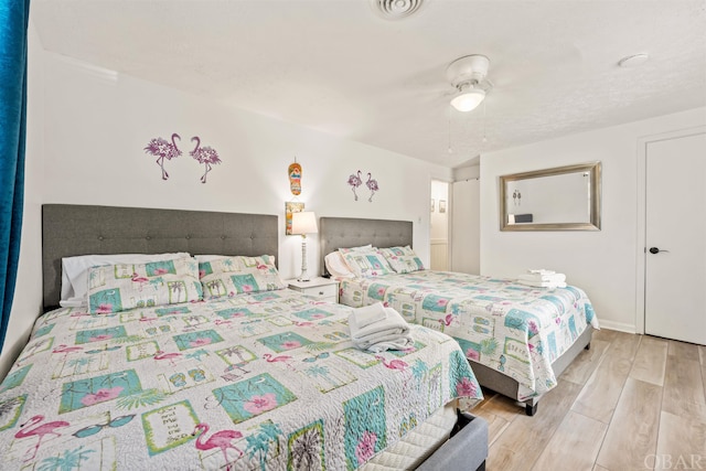 bedroom featuring baseboards, a ceiling fan, visible vents, and light wood-style floors