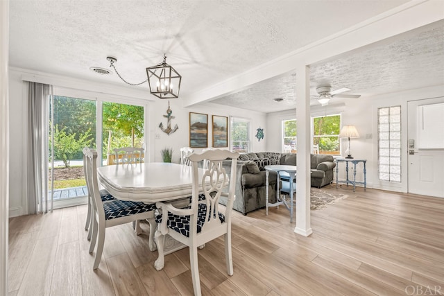 dining space with a textured ceiling, an inviting chandelier, visible vents, and light wood-style floors