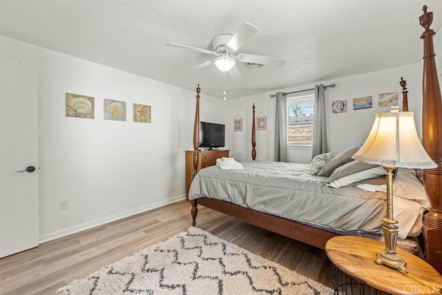 bedroom with baseboards, ceiling fan, a textured ceiling, and light wood finished floors