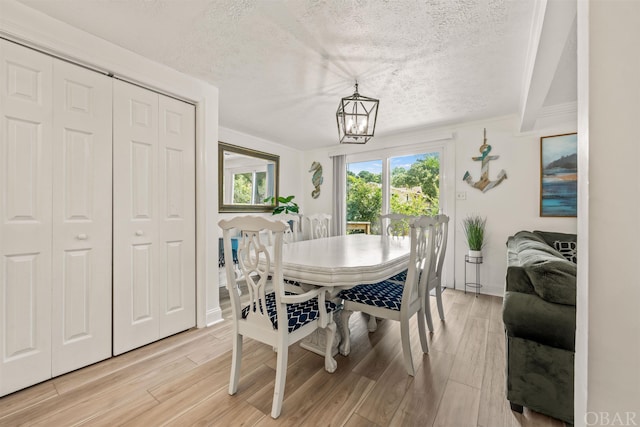 dining space with a chandelier, a textured ceiling, and light wood-style flooring