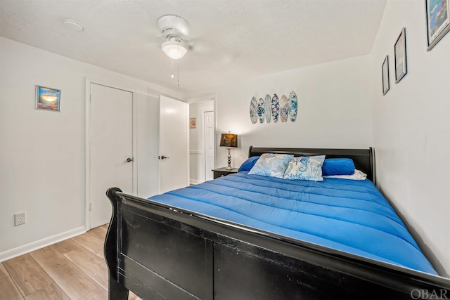 bedroom with a textured ceiling, light wood-type flooring, and baseboards