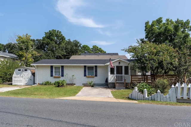 view of front of property with an outbuilding, fence, a front yard, and a storage unit