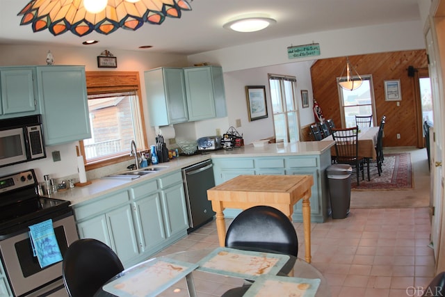 kitchen with stainless steel appliances, a wealth of natural light, light countertops, and a sink