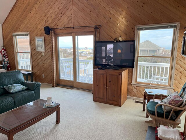 living room featuring lofted ceiling, wooden walls, visible vents, and light colored carpet