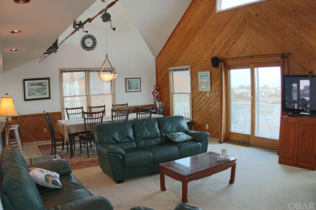 living area with light carpet, high vaulted ceiling, wood walls, and recessed lighting