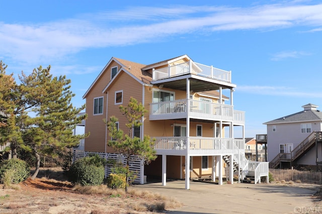 exterior space with stairs, a carport, concrete driveway, and a balcony