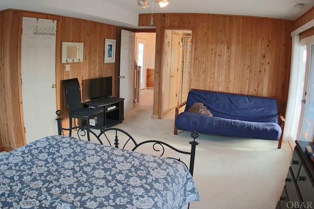 bedroom featuring wood walls and light colored carpet